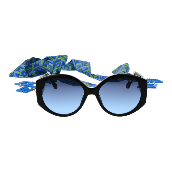 Black cat-eye sunglasses with gradient blue lenses, blue-green patterned scarf and gold chain charms