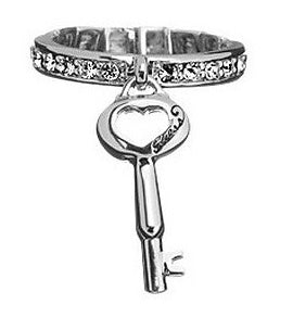 Silver ring with rhinestone band and dangling heart key charm beside a decorative jewelry box